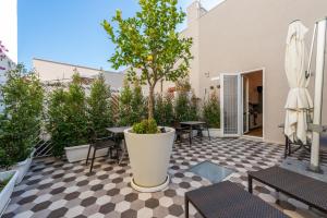 um pátio com uma mesa e uma árvore num piso xadrez em I Colori della Puglia Rooms em Trani