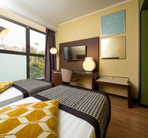a hotel room with two beds and a desk at Holiday Inn Turin Corso Francia by IHG in Turin