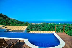 a blue swimming pool on a deck with a view of the ocean at Morro Apartment Vista Mar in Morro de São Paulo +53 photos