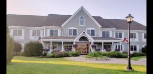 a large house with a flag in front of it at Country Inn at the Mall in Bangor