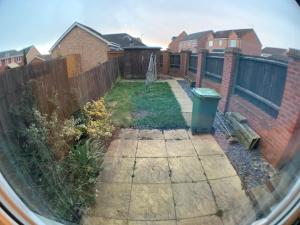 a backyard with a fence and a bench and houses at Harpers brook house, Netflix TVs and fast WIFI in Corby