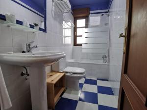 a white bathroom with a sink and a toilet at Hotel El Trasgu in Cangas de Onís