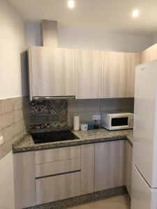 een keuken met witte kasten en een witte magnetron bij apartamento cristina in El Rompido