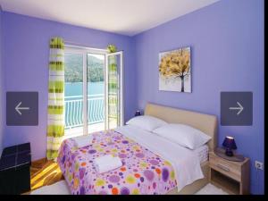 purpurowa sypialnia z łóżkiem i oknem w obiekcie Beach Heaven Home w mieście Slano