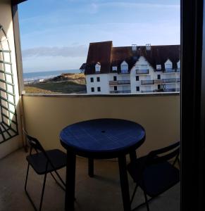 a table and chairs in a balcony with a view of a building at Bord de plage, thalasso et vue mer ! in Cabourg