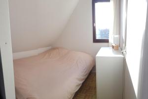 a small white bedroom with a bed and a window at Bord de plage, thalasso et vue mer ! in Cabourg