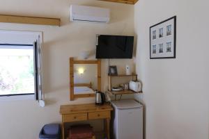 a room with a refrigerator and a tv on the wall at Taxiarchis Apartments in Skiathos