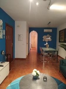 ein Wohnzimmer mit blauen Wänden und einem Tisch in der Unterkunft Apartamento c/piscina centro Nerja in Nerja