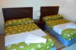 a bedroom with two beds with green and white sheets at Porto Hotel in Lázaro Cárdenas