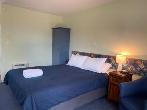 ein Schlafzimmer mit einem Bett mit einer blauen Decke und einem Stuhl in der Unterkunft Studio 3 - Central to Kaikoura! in Kaikoura