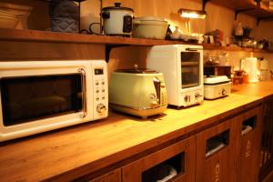 a kitchen counter with a microwave and other appliances on it at Onsen Guest House Tsutaya in Hakone