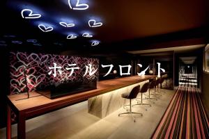 un bar con una fila de taburetes en una habitación en Third Place Hotel en Saitama