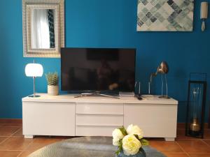ein Wohnzimmer mit einem weißen Entertainment-Center mit einem TV in der Unterkunft Apartamento c/piscina centro Nerja in Nerja