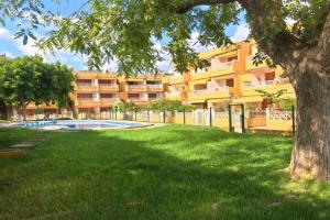 een gebouw met een boom en een tuin met een zwembad bij Apartment Puerto ALCUDIA in Port d'Alcudia