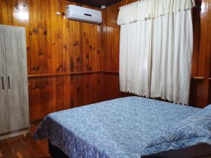 ein Schlafzimmer mit einem Bett mit einer blauen Decke und einem Fenster in der Unterkunft Casa de Ferias Dona Inês in Treze Tílias
