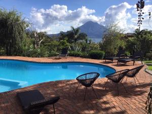 a swimming pool with chairs and a patio with a mountain at Casa Hagan in Santa Cruz La Laguna