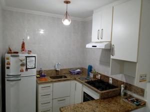 kuchnia z białymi szafkami i białą lodówką w obiekcie Ed.fragatas residence w mieście Bertioga