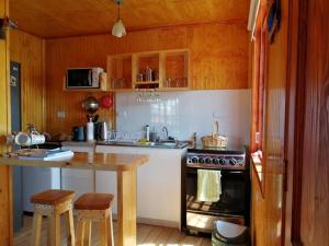 a kitchen with a stove and a counter with stools at CABAÑAS REY-MAR in Castro