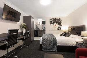 Habitación de hotel con cama, escritorio y sillas en Alabaster Motor Inn en Taree