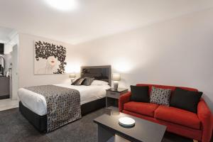 Habitación de hotel con cama y sofá rojo en Alabaster Motor Inn, en Taree