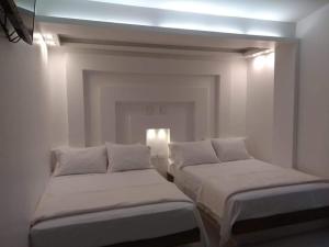 2 bedden in een witte kamer met een licht bij CIELITO LINDO in Santa Rosa de Cabal