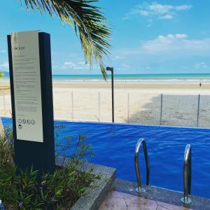 a sign at the beach with a beach in the background at kuantan staycationtimurbay in Kuantan