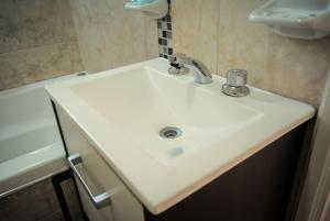 lavabo blanco en el baño junto a la bañera en Lares del Cerro en Sierra de la Ventana