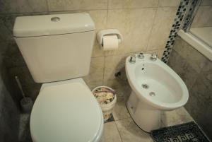 a bathroom with a white toilet and a sink at Lares del Cerro in Sierra de la Ventana