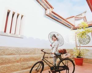 a woman holding an umbrella standing next to a bike at 歇會兒民宿典藏館 in Jincheng