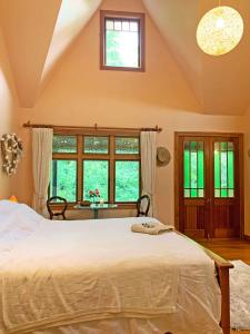 a bedroom with a large bed and windows at Quail Farm, Colonial charm in Nelson