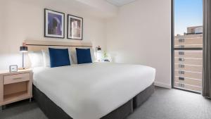 a large white bed with blue pillows in a room at Oaks Brisbane Festival Suites in Brisbane