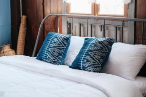 a bed with blue and white pillows on it at บ้านเสงี่ยม-มณี Baan Sa ngiam-Manee in Sakon Nakhon