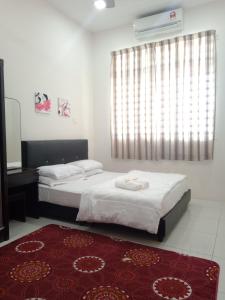 a bedroom with two beds and a window and a rug at Hazz Homestay Alor Setar in Alor Setar