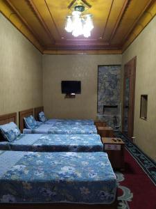 Margilan的住宿－Uvaysiy family guest house，一间设有三张床的客房,墙上设有一台电视。