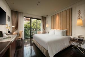 a hotel room with a large bed and a desk at Anatole Hotel Hanoi in Hanoi