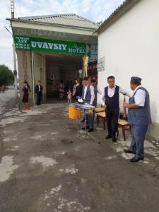 eine Gruppe von Männern, die vor einem Gebäude stehen in der Unterkunft Uvaysiy family guest house in Margilan