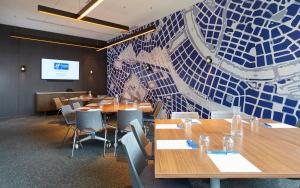 a conference room with wooden tables and chairs and a blue mosaic wall at Holiday Inn Express Melbourne Southbank, an IHG Hotel in Melbourne
