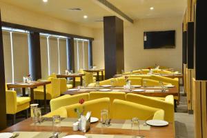Club Central في بولبور: مطعم به كراسي وطاولات صفراء وتلفزيون بشاشة مسطحة