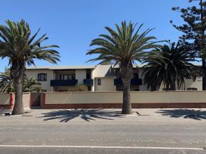 a building with palm trees in front of a street at Good Times Self Catering Apartments in Swakopmund