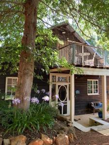 een huis met een veranda en een boom bij Oak Tree Barn Bridgetown in Bridgetown