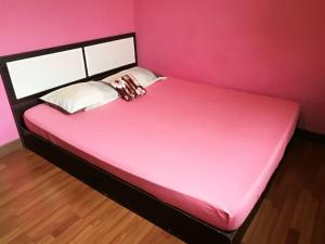 Az Zahra Homestay KLIA Sepang في سيبانغ: غرفة نوم وردية مع سرير بجدار وردي