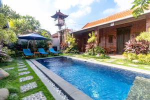 a pool in front of a house with chairs and an umbrella at Pondok Juli Canggu in Canggu +13 photos