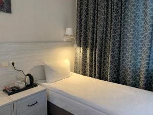 オリョールにあるHotel Aviatorのベッドルーム1室(白いベッド1台、ランプ、カーテン付)