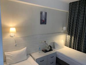 オリョールにあるHotel Aviatorの白いベッドとランプが備わるホテルルームです。