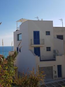 un edificio blanco con ventanas azules y el océano en Galatea House en Marinella di Selinunte