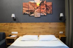 ein Schlafzimmer mit einem Bett mit vier Gemälden an der Wand in der Unterkunft Virginia Hotel in Joschkar-Ola