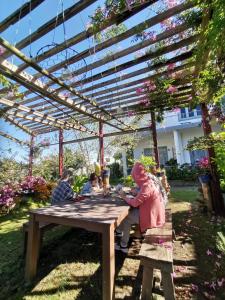 eine Gruppe von Menschen, die an einem Picknicktisch unter einer Pergola sitzen in der Unterkunft Tia Du Homestay in Da Lat