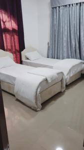 um par de camas num quarto com uma janela em Discovery Furnished Apartments (Al-Amerat) em Sayḩ adh Dhabi