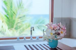 a blue vase with pink and white flowers on a table at Cardamon Hotel Nilaveli in Nilaveli