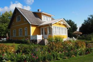 a yellow house with a garden in front of it at Leesi Puhkemaja in Leesi